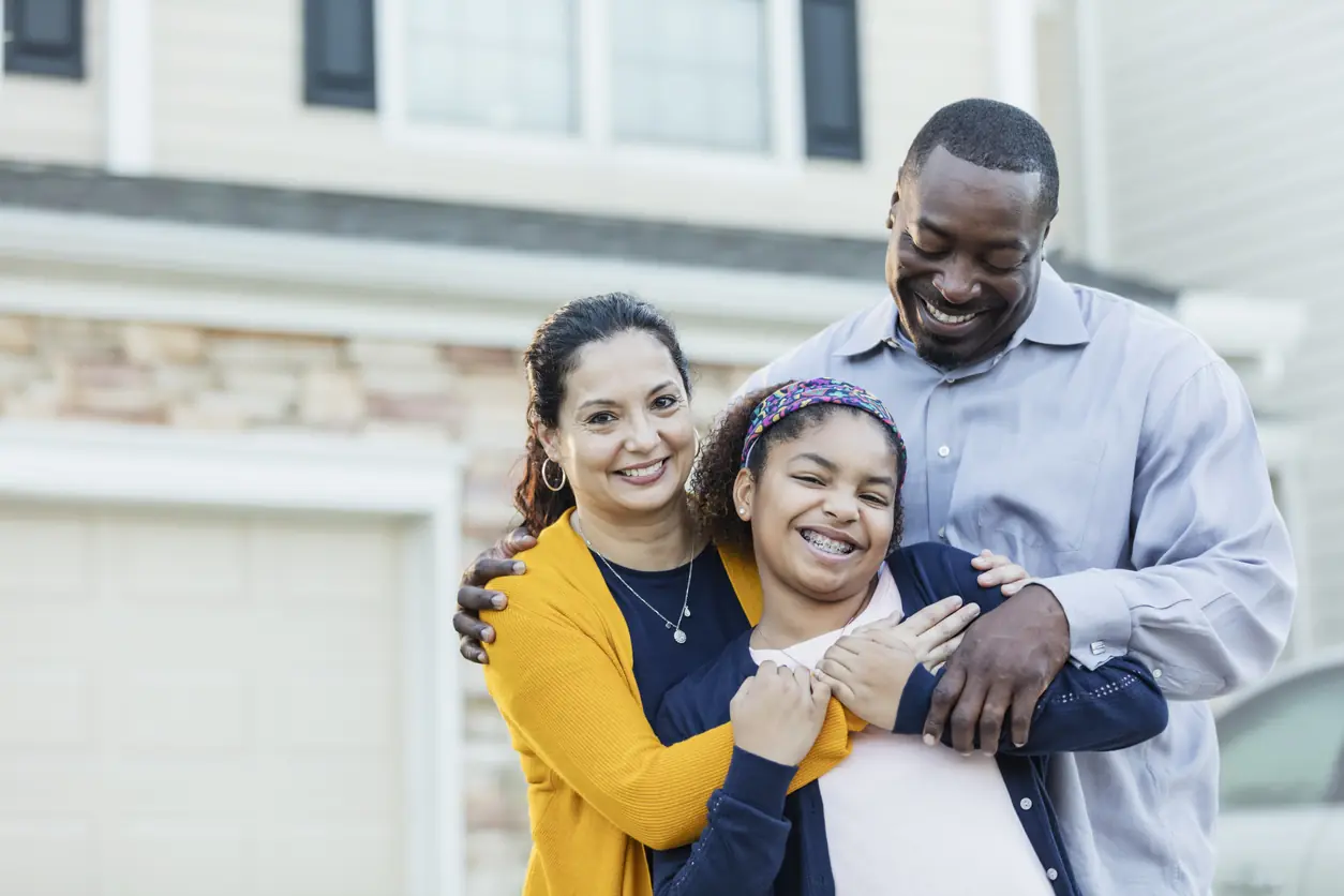Mixed race girl with parents outside home